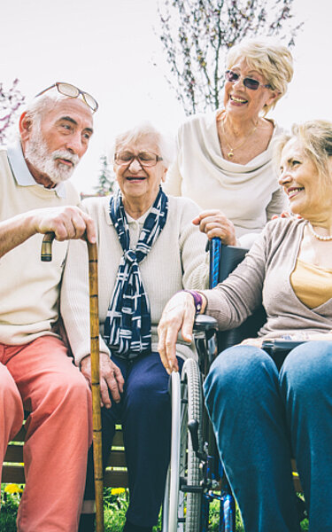 Eine Gruppe von Senioren verbringt seine Zeit lächelnd im Freien.
