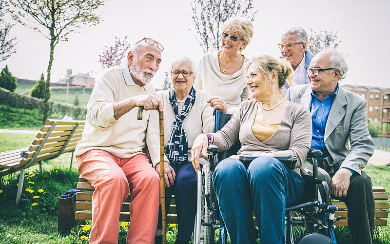 Eine Gruppe von Senioren verbringt seine Zeit lächelnd im Freien.