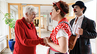ROTE NASEN Clowns unterhalten sich mit einer Seniorin im Pflegeheim.